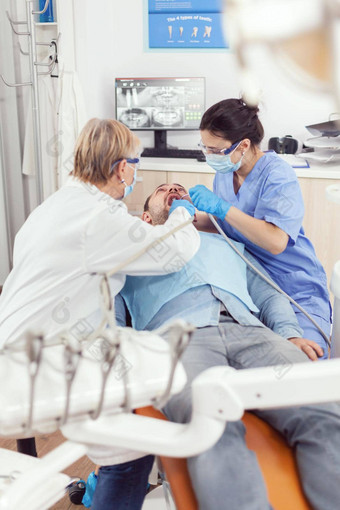 高级女人口腔学家分析镜子生病的病人牙健康