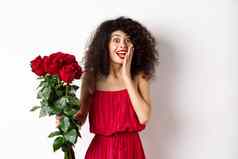 兴奋卷曲的女人红色的衣服收到花束玫瑰惊喜欢乐浪漫的礼物站白色背景