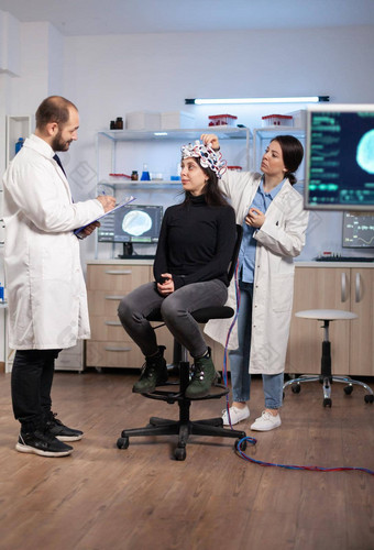 专业神经系统研究员explaning治疗结果医疗科学家调整脑电图耳机