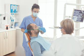 口腔学家护士把氧面具病人检查牙痛