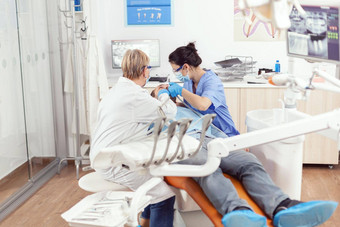 医院牙医团队清洁牙齿生病的男人。准备口腔学手术