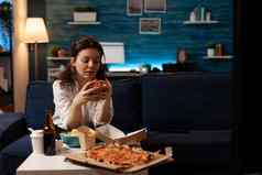 女人坐着沙发吃美味的美味的汉堡看纪录片电影电视