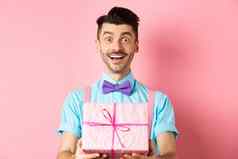 假期庆祝活动概念快乐的的家伙祝快乐生日给礼物包装盒子站粉红色的背景节日衣服