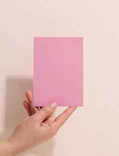 女手持有空粉红色的纸米色背景复制粘贴图像文本关闭