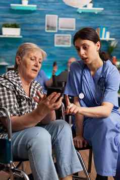 护士帮助退休高级女人轮椅智能手机社会服务