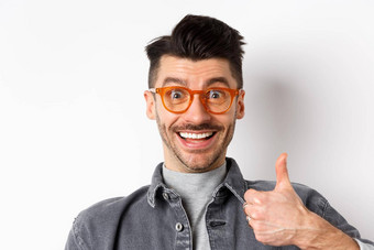关闭肖像兴奋有趣的的家伙眼镜显示拇指微笑支持赞美推荐很酷的商店站白色背景