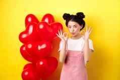 可爱的年轻的亚洲女人时尚的衣服化妆显示迹象情人节一天心气球赞美好提供站黄色的背景