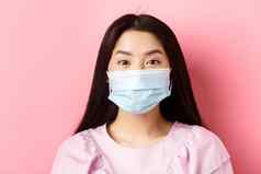 科维德健康的人概念特写镜头亚洲可爱的女孩穿医疗面具病毒爆发站粉红色的背景