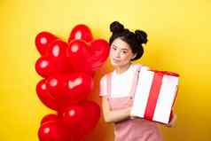 快乐情人节一天美丽的时尚的亚洲女人摆姿势心气球可爱的盒子礼物情人站黄色的背景