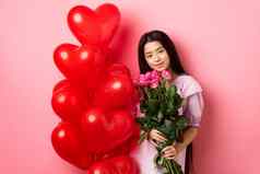 情人节一天概念温柔的温柔的十几岁的女孩持有浪漫的花站红色的心气球情人盯着爱站粉红色的背景