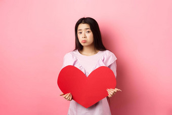 情人节概念单十几岁的亚洲女孩秋天爱伤心孤独的相机生闷气的陷入困境的情人一天持有大红色的心断路粉红色的背景
