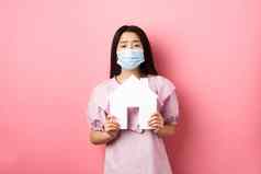 真正的房地产流感大流行概念乞讨亚洲女孩显示纸房子断路穿医疗面具公寓站粉红色的背景