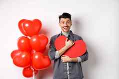 年轻的浪漫的男人。爱相机拥抱情人节心卡微笑快乐庆祝情人假期站红色的气球白色背景