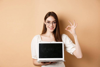 电子商务微笑年轻的女人眼镜显示标志移动PC屏幕推荐互联网促销站米色背景