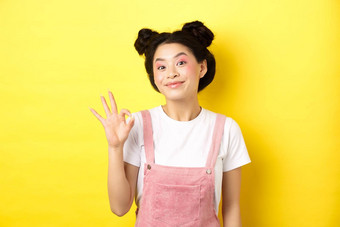 快乐的亚洲美女孩化妆显示标志微笑兴奋批准好促销推荐产品黄色的背景