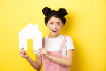 真正的房地产家庭概念可爱的亚洲女人明亮的化妆时尚的发髻显示纸房子断路微笑确定黄色的背景