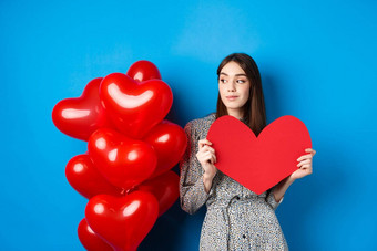 情人节一天浪漫的女孩衣服站气球持有大红色的心断路梦想站蓝色的背景