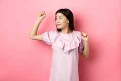 无忧无虑的亚洲女孩跳舞提高手左标志站浪漫的衣服粉红色的背景