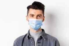 流感大流行生活方式医疗保健医学概念关闭坦诚的年轻的男人。穿医疗面具科维德采取护理健康站白色背景