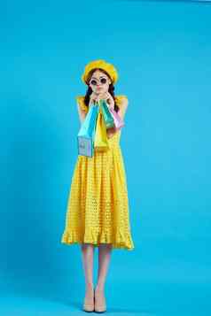 快乐的女人黄色的衣服购物有趣的蓝色的背景