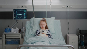 肖像<strong>住院</strong>生病的女孩孩子病人持有泰迪熊休息床上医疗咨询