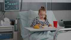 肖像住院孩子休息床上吃健康的食物餐复苏检查