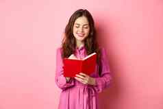有吸引力的现代女人写作日记使笔记笔记本规划师时间表站粉红色的背景