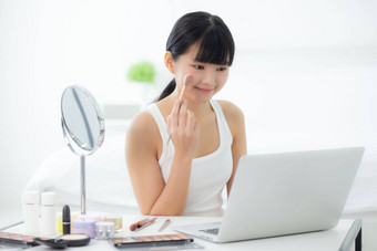 美年轻的亚洲女人学习化妆刷脸颊移动PC电脑教程在线女教学解释使化妆品流媒体社会媒体