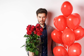 男子气概男人。浪漫的日期自信相机持有礼物情人情人节一天站心气球红色的玫瑰白色背景