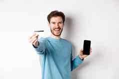 电子商务购物概念快乐男人。显示塑料信贷卡屏幕智能手机推荐银行应用程序站白色背景