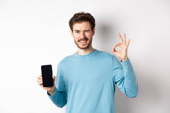 电子商务购物概念微笑的家伙眨眼显示标志空智能手机屏幕推荐在线提供站白色背景