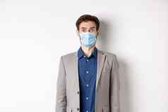 健康流感大流行业务概念惊讶的家伙西装医疗面具提高眉毛站在震惊了相机白色背景