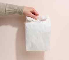 女手持有完整的纸袋米色背景拒绝塑料包装食物交付
