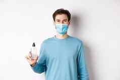 科维德健康检疫概念肖像微笑男人。医疗面具显示手洗手液瓶站白色背景