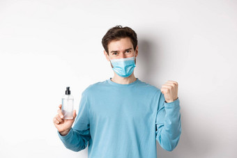 科维德健康检疫概念快乐的男人。脸面具庆祝显示拳头泵瓶手洗手液战斗细菌白色背景