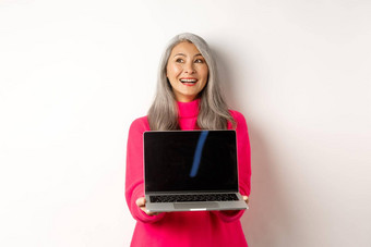 电子商务概念快乐美丽的亚洲高级女人灰色头发微笑显示移动PC黑色的屏幕站白色背景