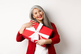 快乐亚洲祖母拥抱红色的礼物盒子微笑感激的感谢现在站白色背景