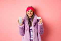在线购物时尚概念时尚亚洲高级女人显示黑色的屏幕智能手机塑料信贷卡微笑快乐粉红色的背景