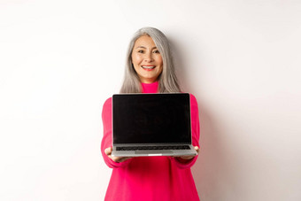 电子商务概念微笑亚洲高级女人显示空白移动PC屏幕快乐展示促销白色背景