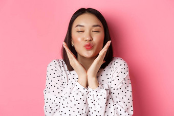 美皮肤护理概念特写镜头美丽的亚洲女孩关闭眼睛皱纹嘴唇吻显示可爱的完美的脸站粉红色的背景