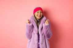 快乐的亚洲夫人时尚的时髦的外套庆祝胜利成功微笑快乐站粉红色的背景