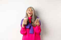 社会网络快乐亚洲高级女人喝咖啡持有智能手机笑相机站白色背景