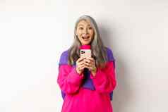 惊讶亚洲女人微笑相机阅读促销活动智能手机站移动电话白色背景