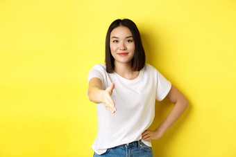 自信亚洲女人白色t恤拉伸手握手问候手势介绍站黄色的背景
