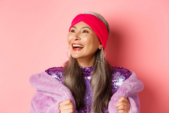时尚特写镜头快乐亚洲高级女人微笑左快乐的脸站紫色的人造皮毛外套粉红色的背景