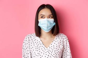科维德流感大流行生活方式概念美丽的亚洲女模型医疗面具笑微笑左复制空间站粉红色的背景