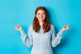 微笑自信女孩红色的头发住病人持有手Zen冥想构成盯着相机<strong>实践</strong>瑜伽<strong>站</strong>平静蓝色的背景