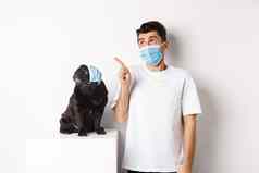科维德动物检疫概念年轻的男人。黑色的狗穿医疗面具哈巴狗老板上左角落里白色背景