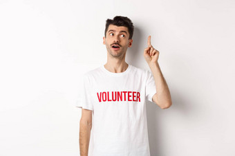 英俊的年轻的男人。志愿者t恤的想法提高手指建议白色背景
