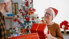 快乐高级夫妇享受圣诞节期分享包装器礼物现在圣诞节装饰厨房